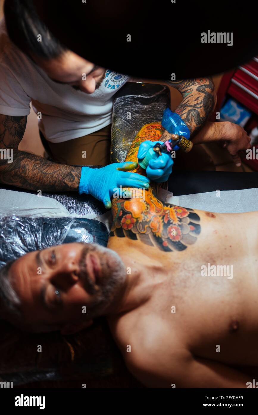 Vue aérienne d'un tatouage artiste travaillant sur le bras d'un client. Banque D'Images