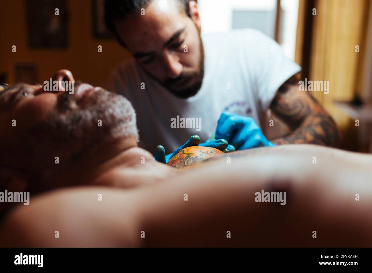 Vue de face d'un tatouage artiste travaillant avec un client dans son studio. Banque D'Images