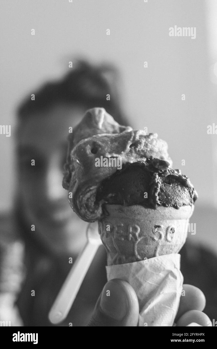Prise de vue verticale en niveaux de gris d'une femelle tenant un cône de glace en fusion Banque D'Images