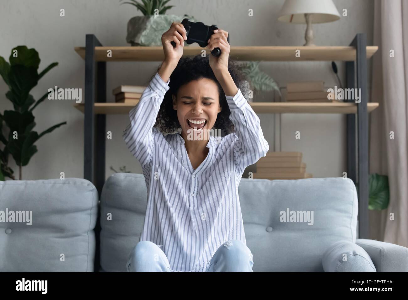 Une femme biraciale joyeuse joue à des jeux vidéo sur ordinateur Banque D'Images