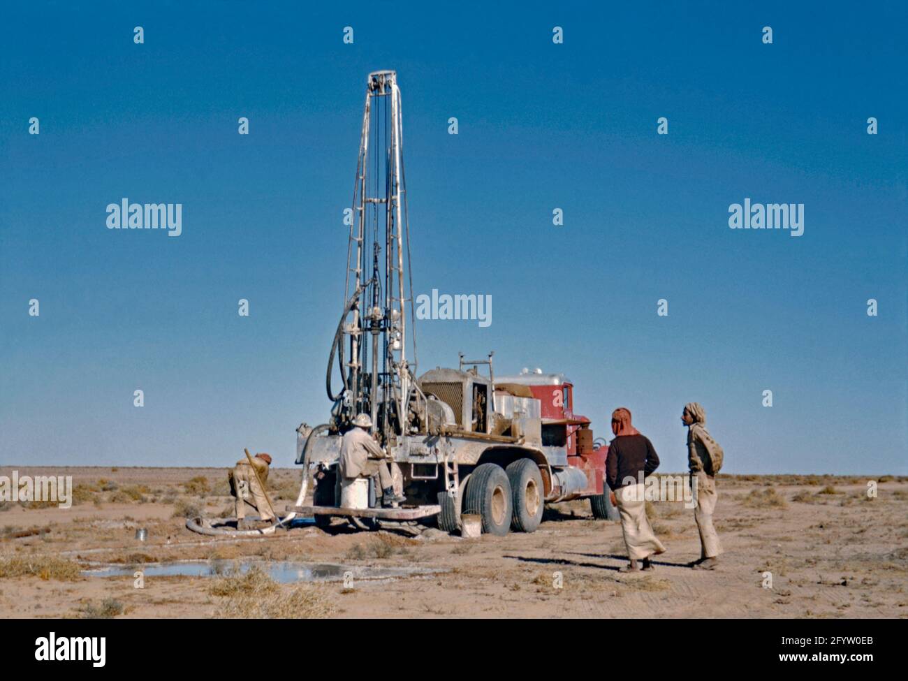 Exploration pétrolière par la compagnie pétrolière Aramco en Arabie Saoudite c. 1955. Ici, un engin de forage mobile à l'arrière d'un camion est un forage d'essai dans le désert. Saudi Aramco (maintenant la Saudi Arabian Oil Company et anciennement Arabian-American Oil Company) est une société saoudienne de pétrole et de gaz naturel basée à Dhahran. En 1944, le nom de la société est passé de la California-Arabian Standard Oil Company à la Arabian-American Oil Company (ou Aramco), une photographie vintage des années 1950. Banque D'Images