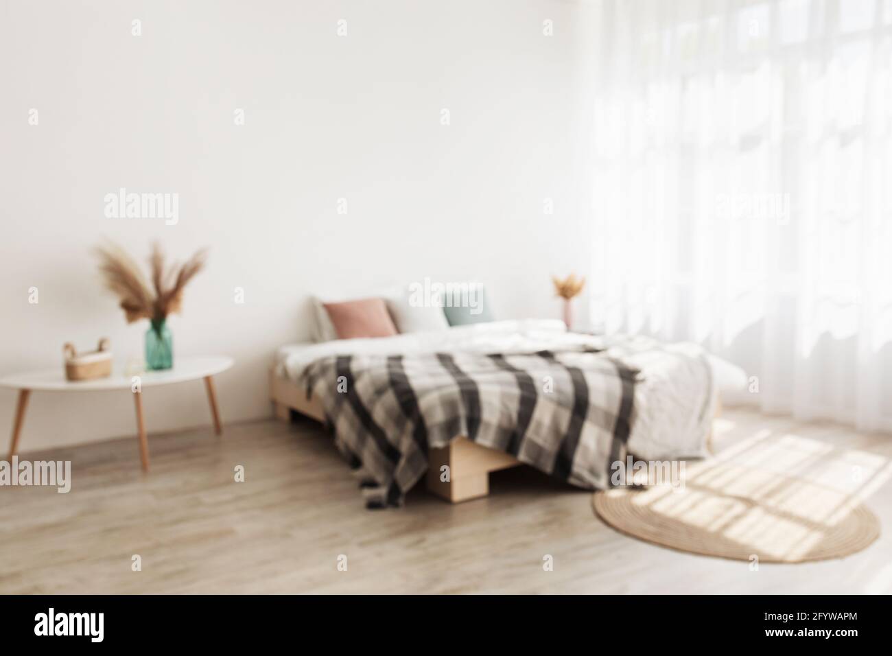 Intérieur confortable et style minimaliste. Lit double avec oreillers et couverture, tables avec plantes sèches dans des vases Banque D'Images