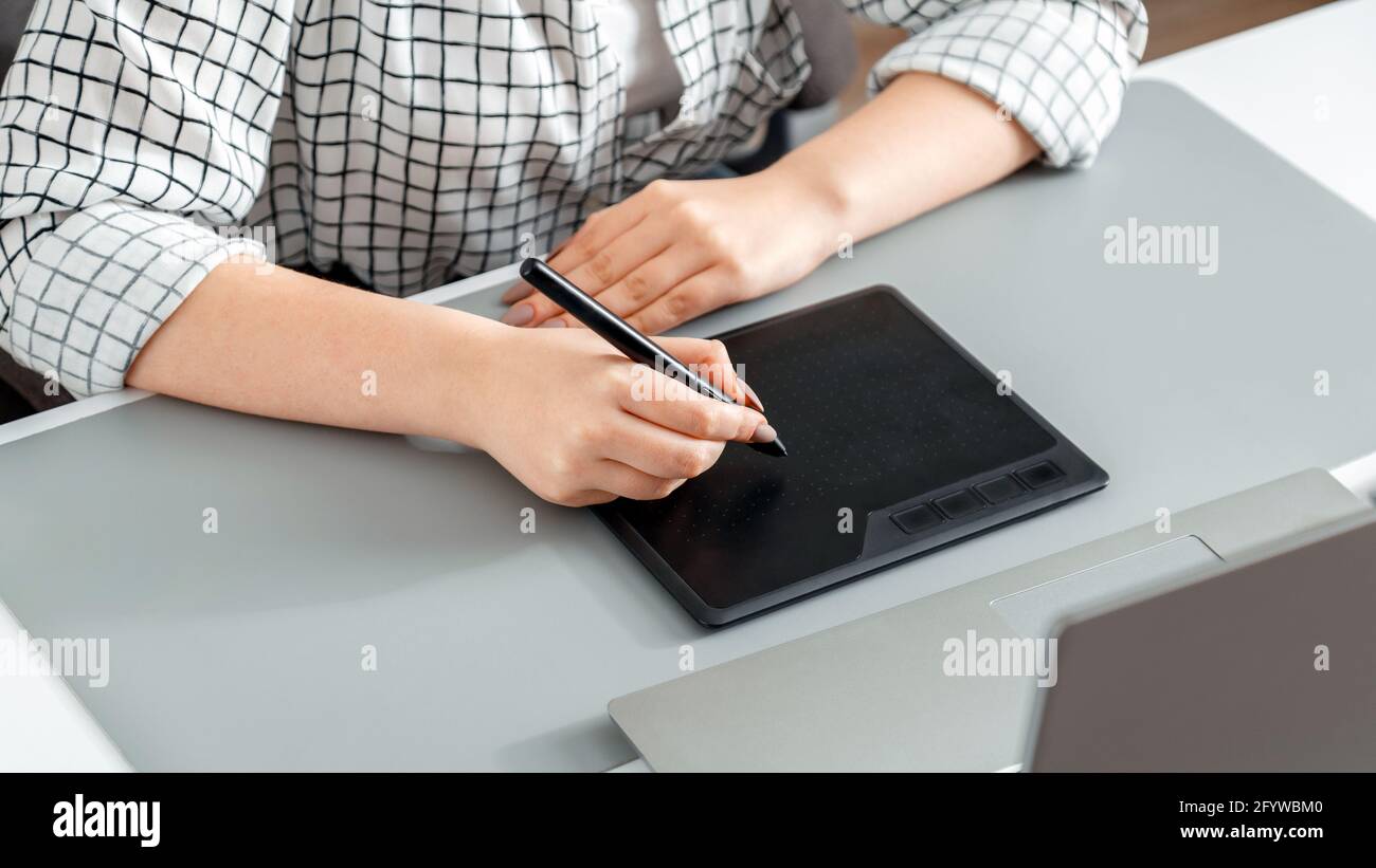 Créateur travaillant avec des équipements professionnels. Le stylet dessine sur la tablette graphique. Une femme de créateur, éditeur ou photographe, utilise une tablette graphique Banque D'Images