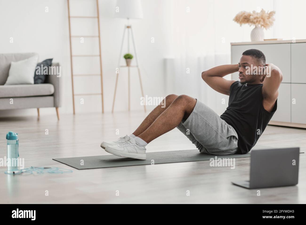 Vue latérale de l'Afro-américain Guy faisant SIT-UPS à l'intérieur d'ordinateur portable Banque D'Images
