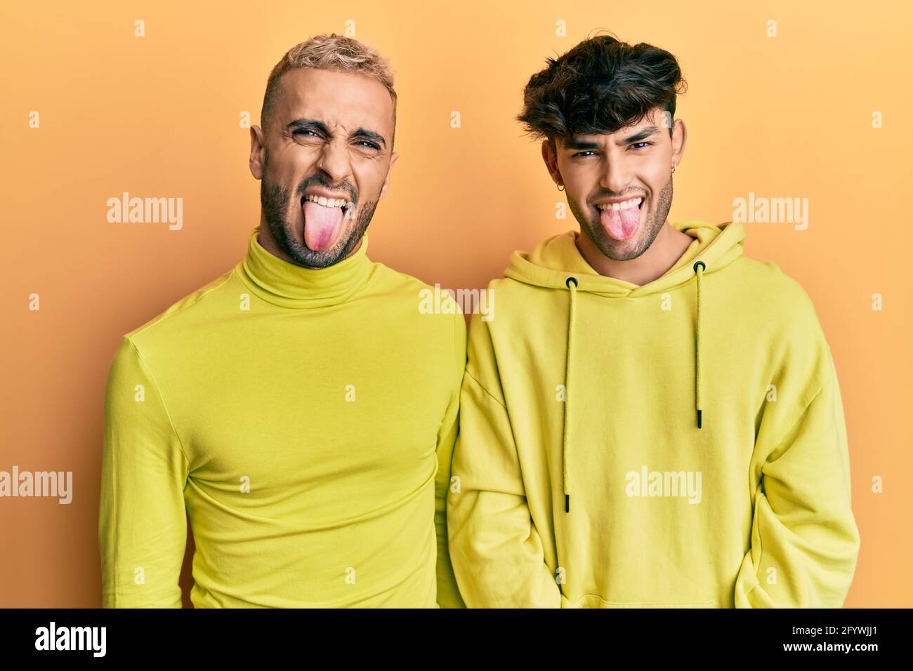 Homosexuel gay couple debout ensemble portant des vêtements jaunes collant  la langue dehors heureux avec l'expression drôle. Concept d'émotion Photo  Stock - Alamy