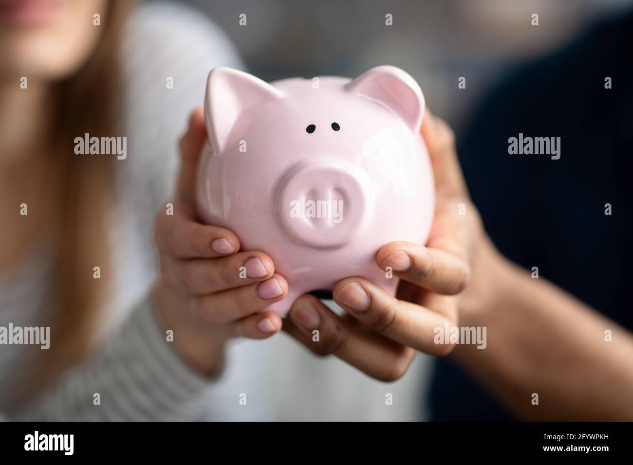Couple méconnaissable tenant Pink Piggybank entre les mains, économisant de l'argent pour l'avenir Banque D'Images