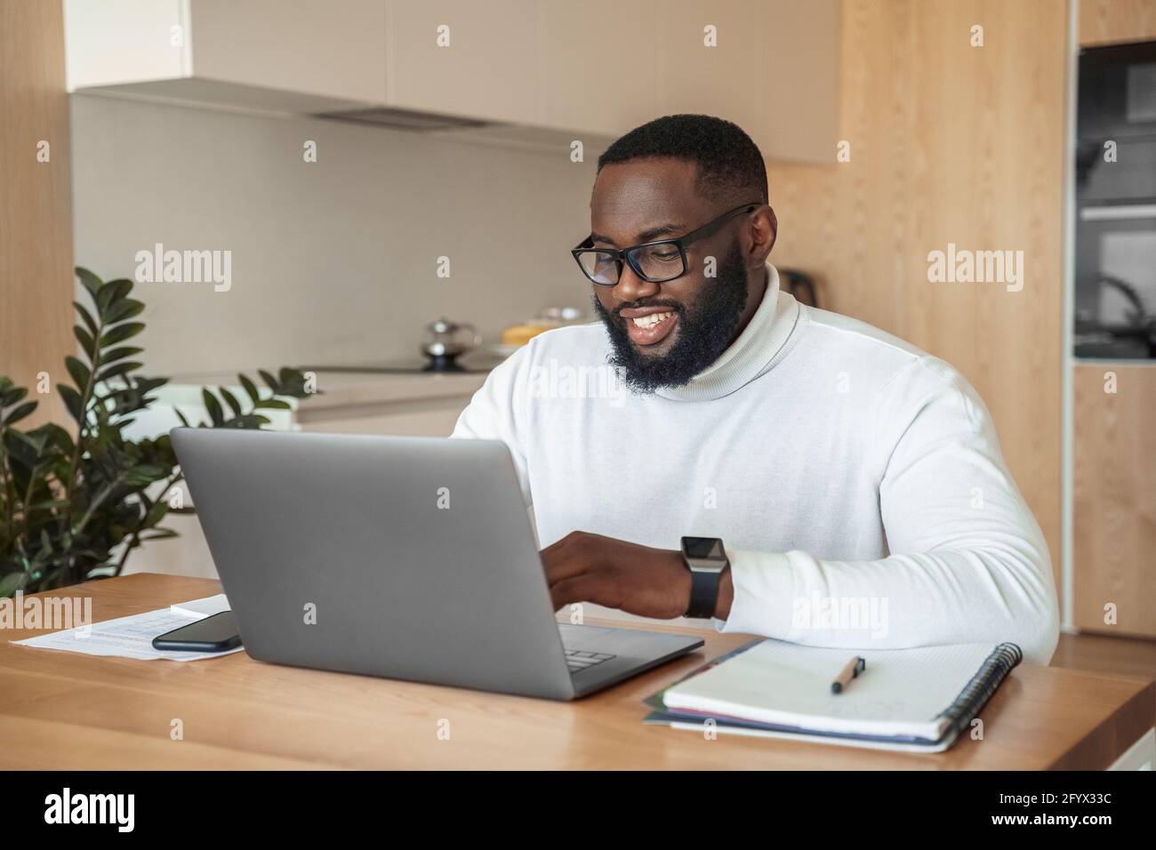 Jeune afro-américain souriant indépendant étudiant ou travaillant en ligne sur ordinateur portable Banque D'Images