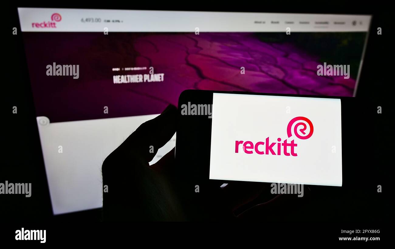 Personne détenant un smartphone avec le logo de la société de biens de consommation Reckitt Benckiser Group plc à l'écran devant la page Web. Concentrez-vous sur l'affichage du téléphone portable. Banque D'Images