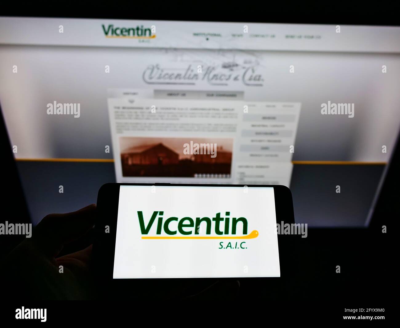 Personne tenant un smartphone avec le logo du conglomérat argentin Vitentin S.A.I.C. à l'écran devant le site. Mise au point sur l'affichage du téléphone. Banque D'Images