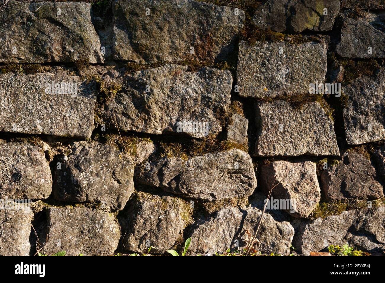 un mur de pierres de granit rugueuses, avec de la mousse dans les fissures Banque D'Images