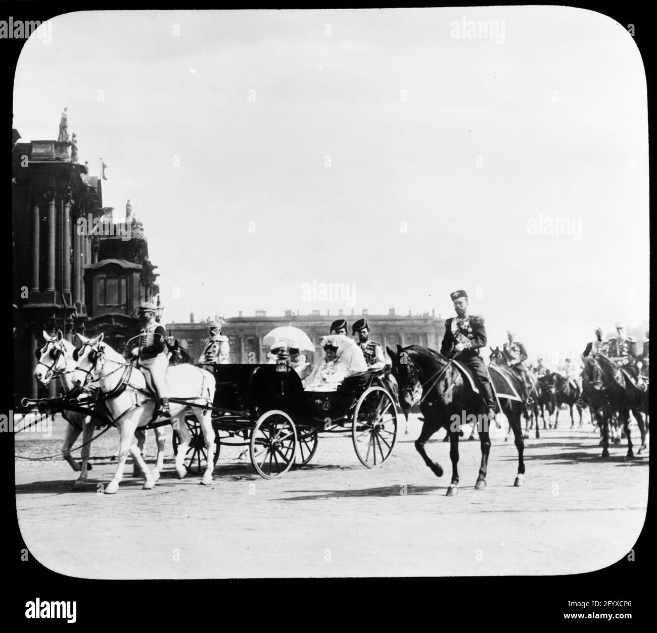 Le tsar russe Nicholas II (1868 - 1918) à côté d'une calèche transportant son épouse, la russe Tsarina Alexandra Feodorovna d'origine allemande, également connue sous le nom d'Alix de Hesse, (1872 - 1918) mère, l'impératrice danoise Maria Feodorovna (1847 - 1928) et sœur, la Grande Duchesse russe Olga Alexandrovna (1882 - 1960) Défilé du Palais d'hiver, Saint-Pétersbourg, Russie, 1901. Le cortège impérial se déplace vers un examen des troupes. (Photo de Burton Holmes) Banque D'Images