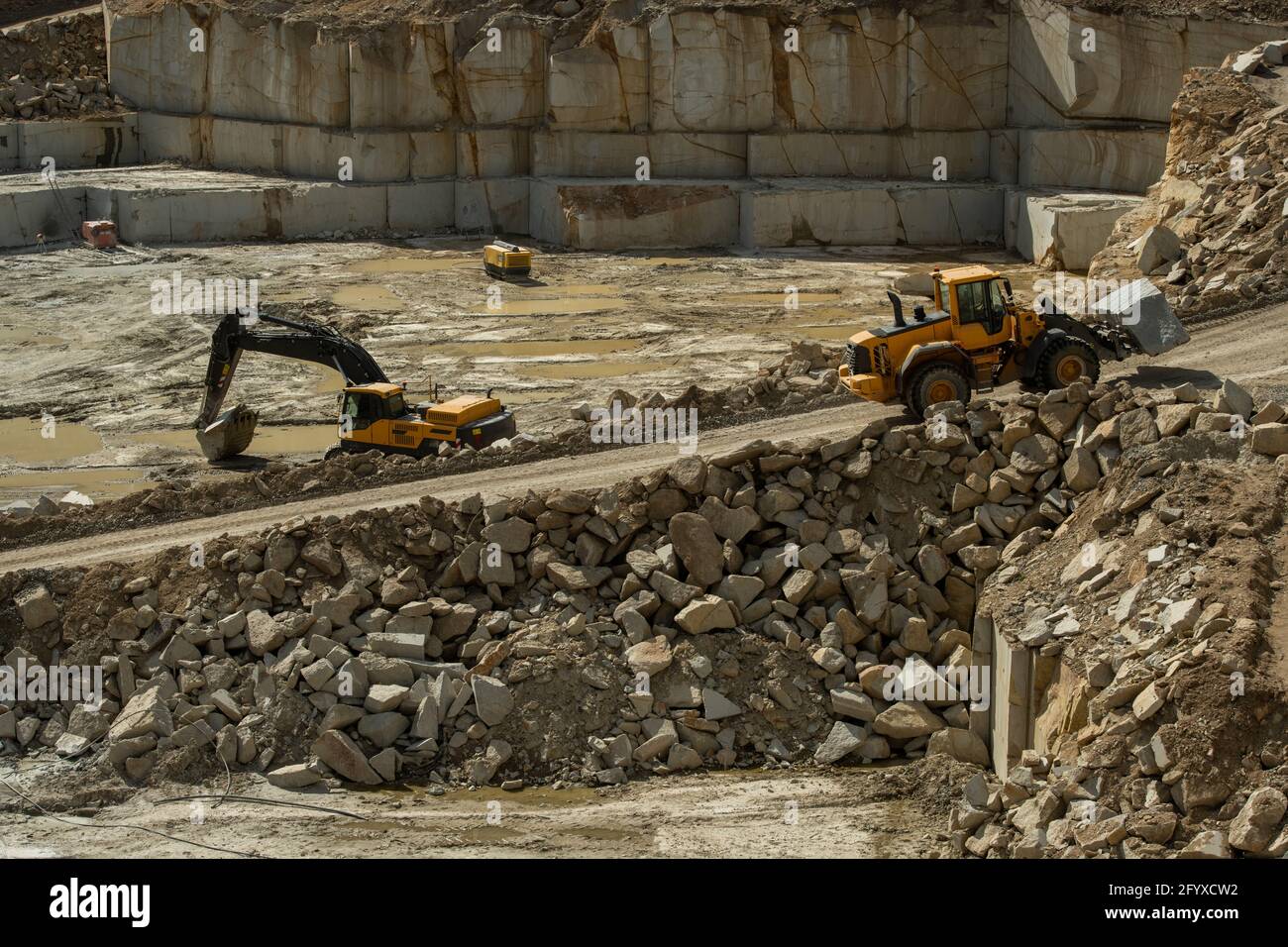 Tracteur se déplaçant sur une route étroite contre le chantier avec des machines Banque D'Images