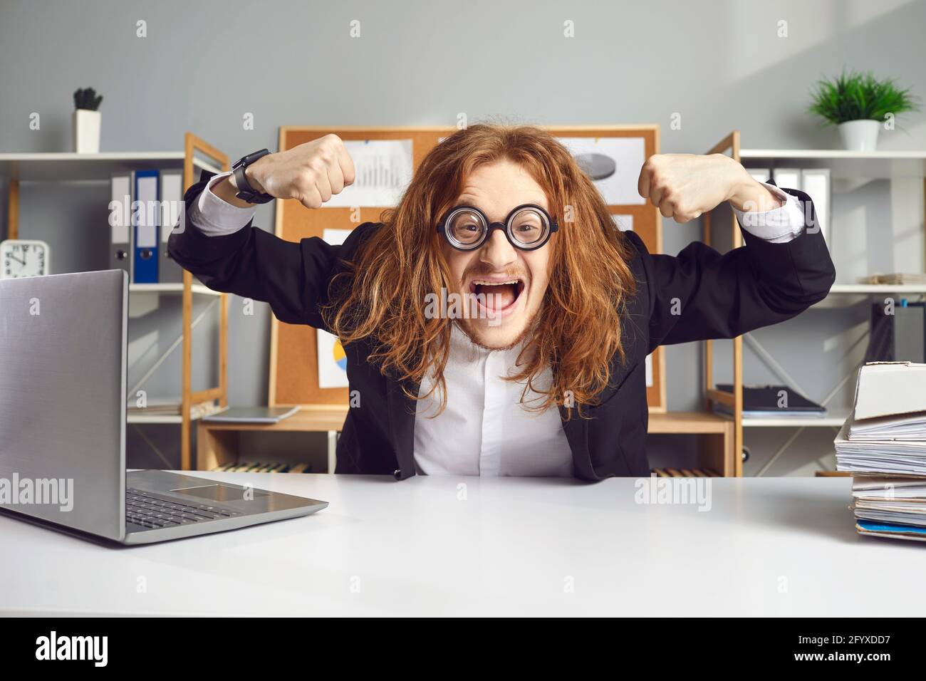 Drôle de travailleur de bureau assis au bureau et de flexion des muscles  heureux pour commencer une journée de travail Photo Stock - Alamy