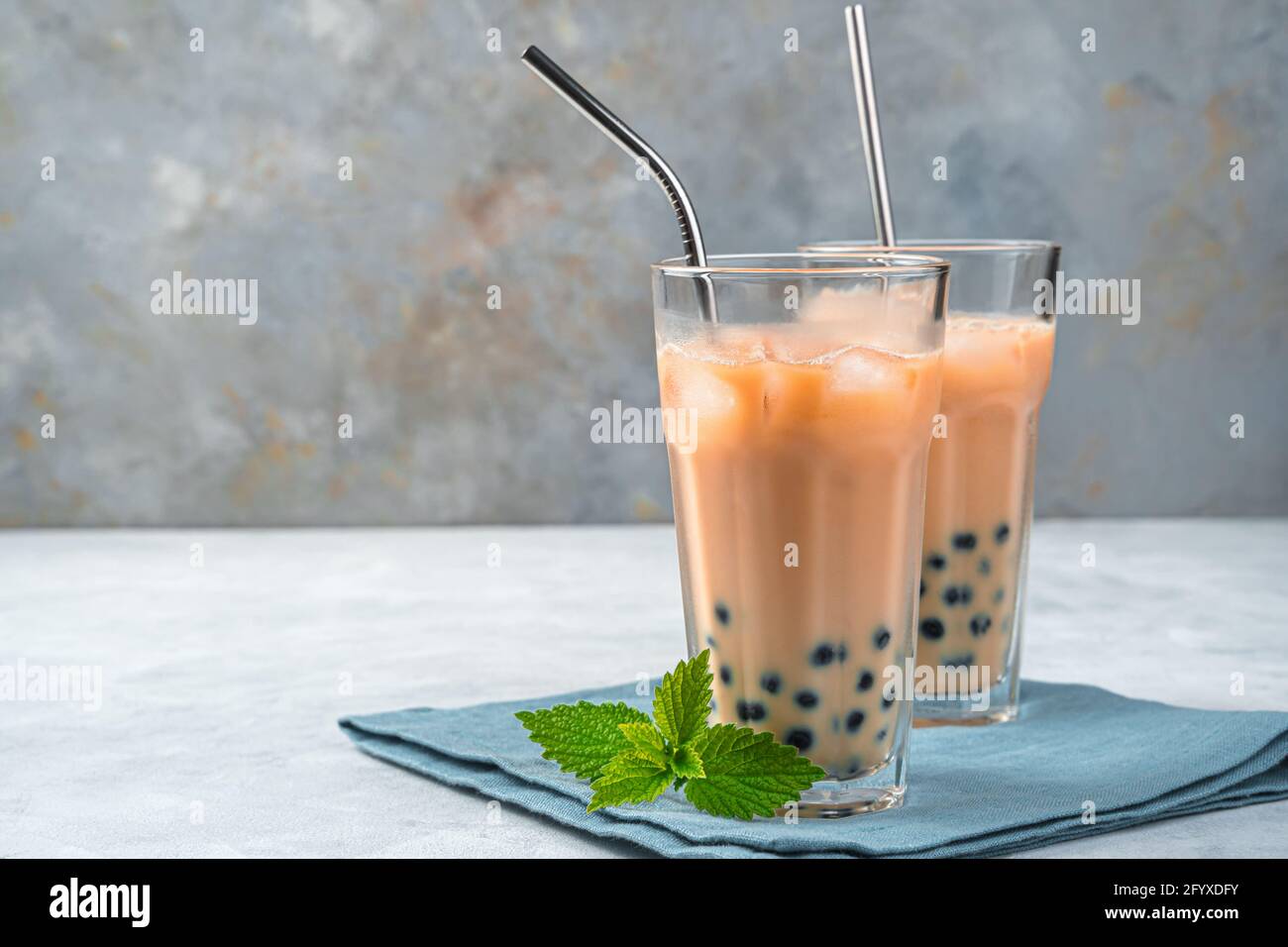 Deux verres de thé de tapioca sur fond gris avec espace de copie. Thé moussant au lait maison avec perles de tapioca. Boisson rafraîchissante taïwanaise. Banque D'Images