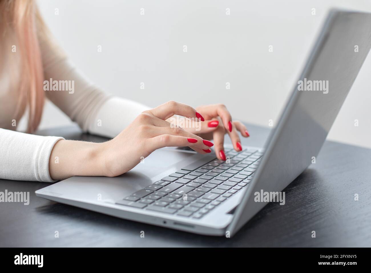 Sélection de la mise au point douce belle main femelle sont la saisie de texte sur le clavier d'ordinateur portable. Manucure rouge vif. Concept de travail dans le bureau de femme d'affaires et com Banque D'Images