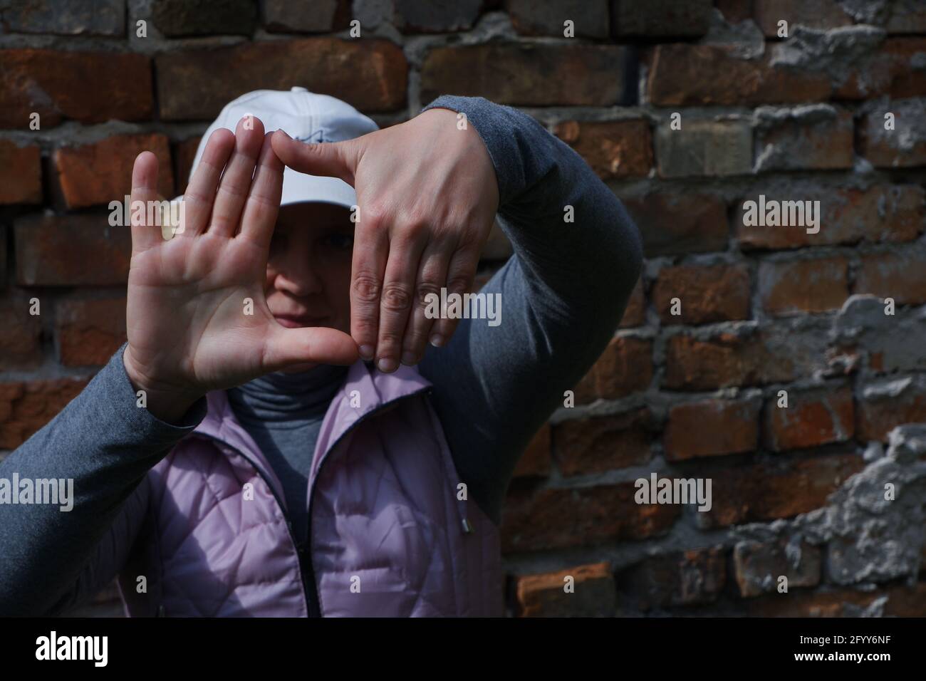 Une fille près d'un mur de briques avec ses mains imagine un appareil photo. Journée des photographes de la Saint-Veronica . Banque D'Images