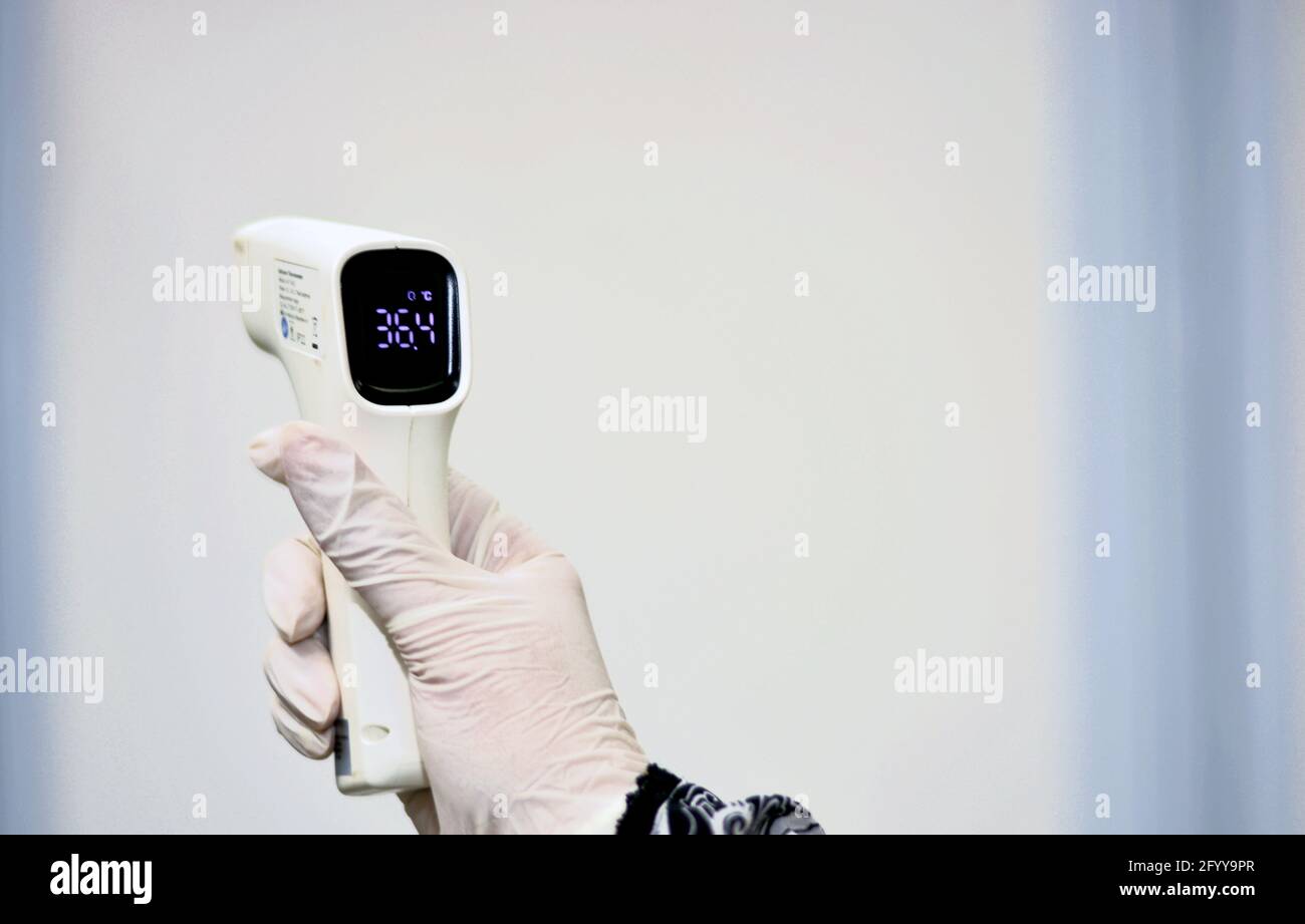 Thermomètre numérique frontal infrarouge sans contact tenu par un personnel médical qui vérifie la température du corps à la recherche de symptômes de virus Banque D'Images