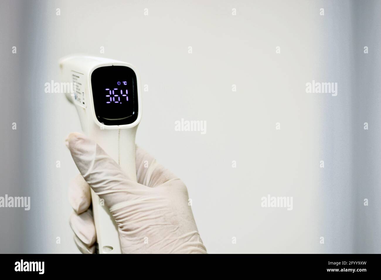 Thermomètre numérique frontal infrarouge sans contact tenu par un personnel médical qui vérifie la température du corps à la recherche de symptômes de virus Banque D'Images