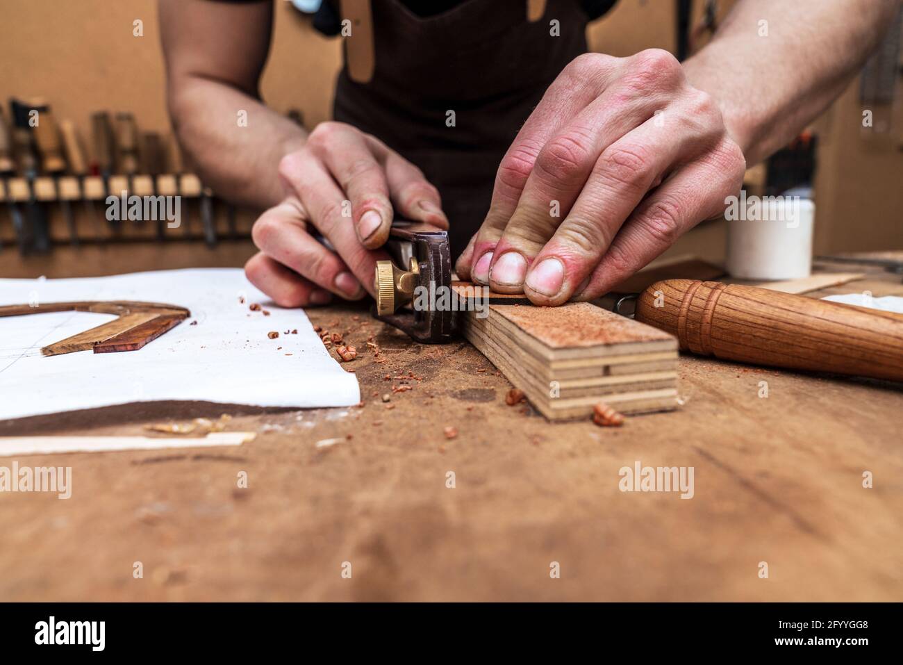 Récolte de l'artisan non reconnaissable coupant une pièce en bois avec une jointer sur la barre de coupe avec feuille de papier dans l'atelier Banque D'Images