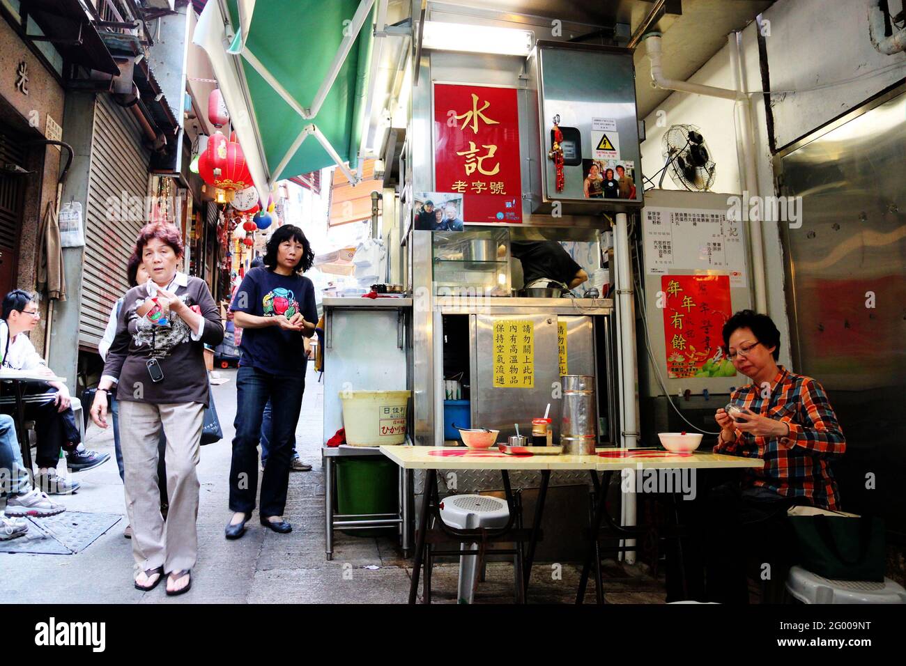 HONG KONG - APR. 19, 2011: La foule de l'heure du déjeuner manger dans les stands de nourriture de rue en plein air connu sous le nom de Dai Pai Dong dans le centre de Hong Kong. Ces cuisines extérieures le sont Banque D'Images