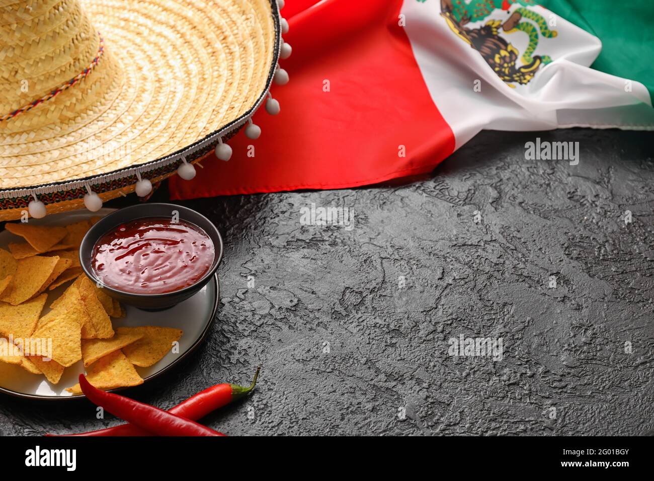 Drapeau mexicain, chapeau de sombrero, piments, nachos et sauce sur fond  sombre, gros plan Photo Stock - Alamy