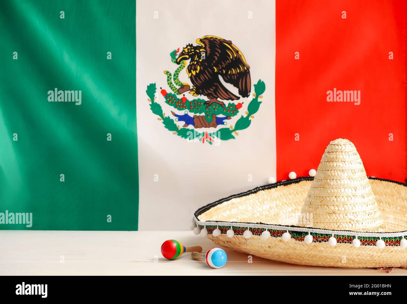 Chapeau Sombrero et maracas à table contre le drapeau mexicain Photo Stock  - Alamy