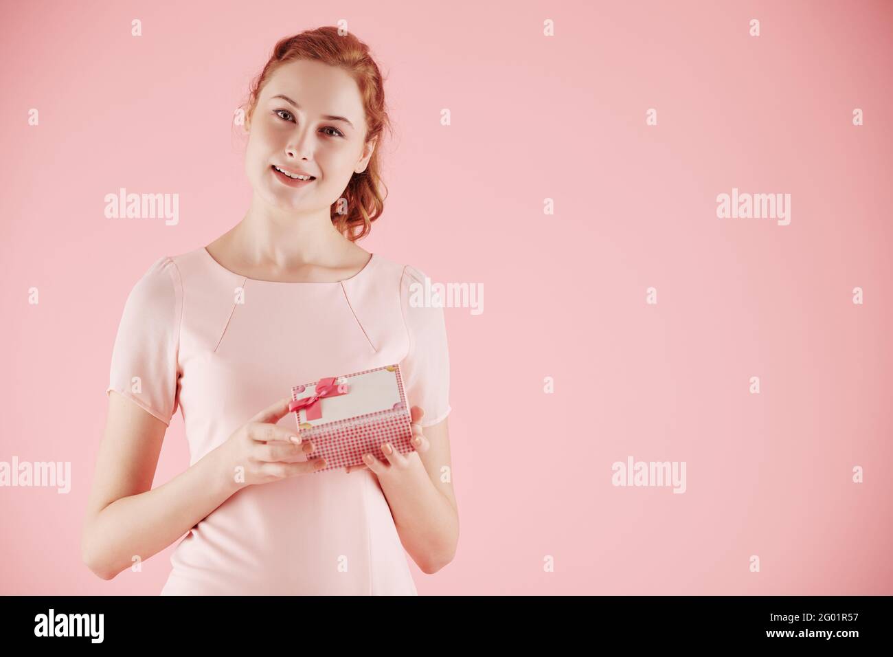 Portrait de charmante jeune femme ouvrant petite boîte-cadeau et regarder l'appareil photo Banque D'Images