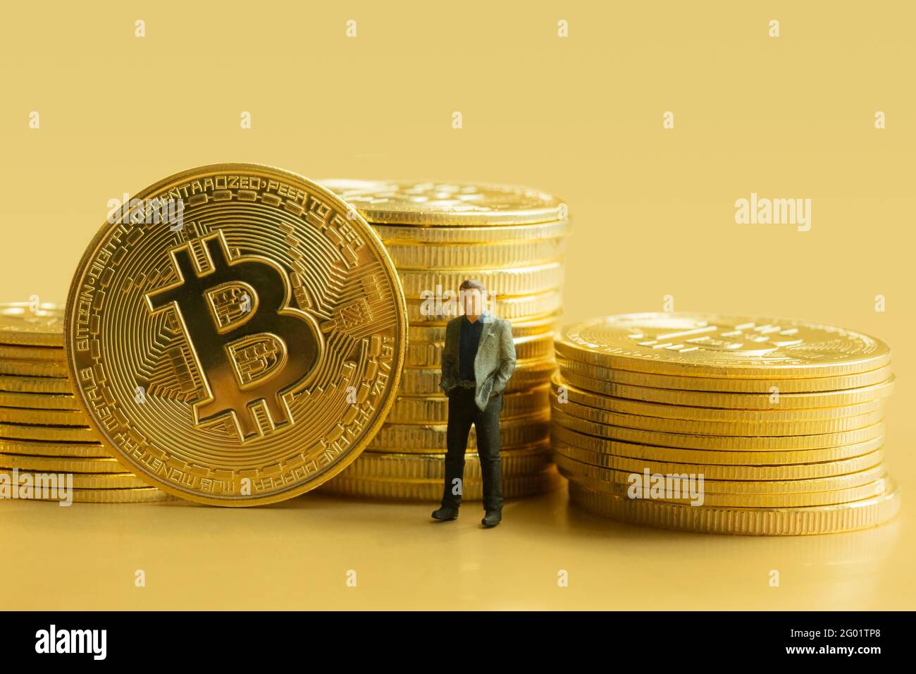 Pile de bitcoins avec homme d'affaires miniature sur fond doré. Concept de crypto-monnaie. Banque D'Images