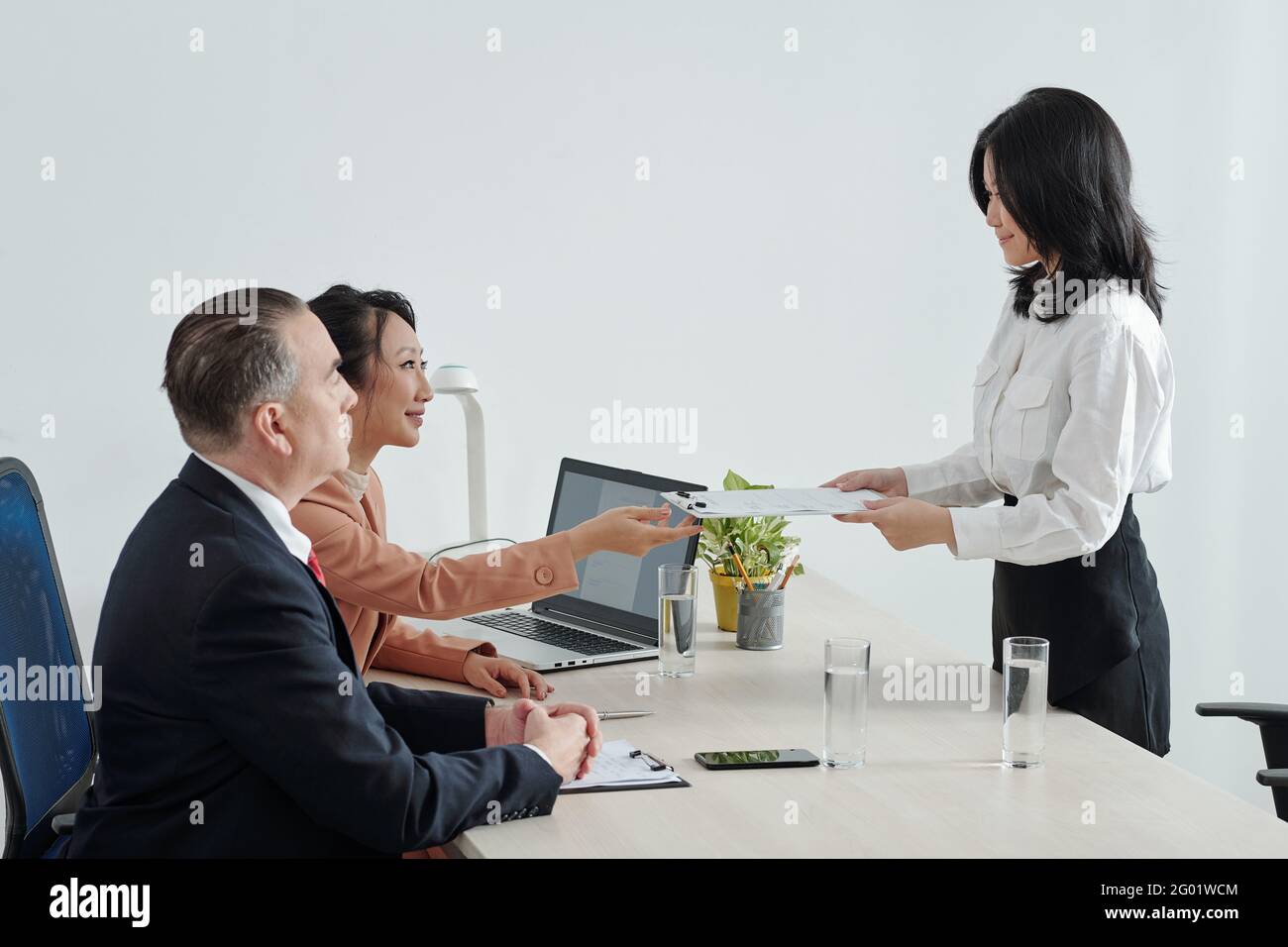 Jeune candidat souriant donnant un curriculum vitae imprimé aux RH directeur général et PDG de l'entreprise avant l'entretien d'embauche Banque D'Images