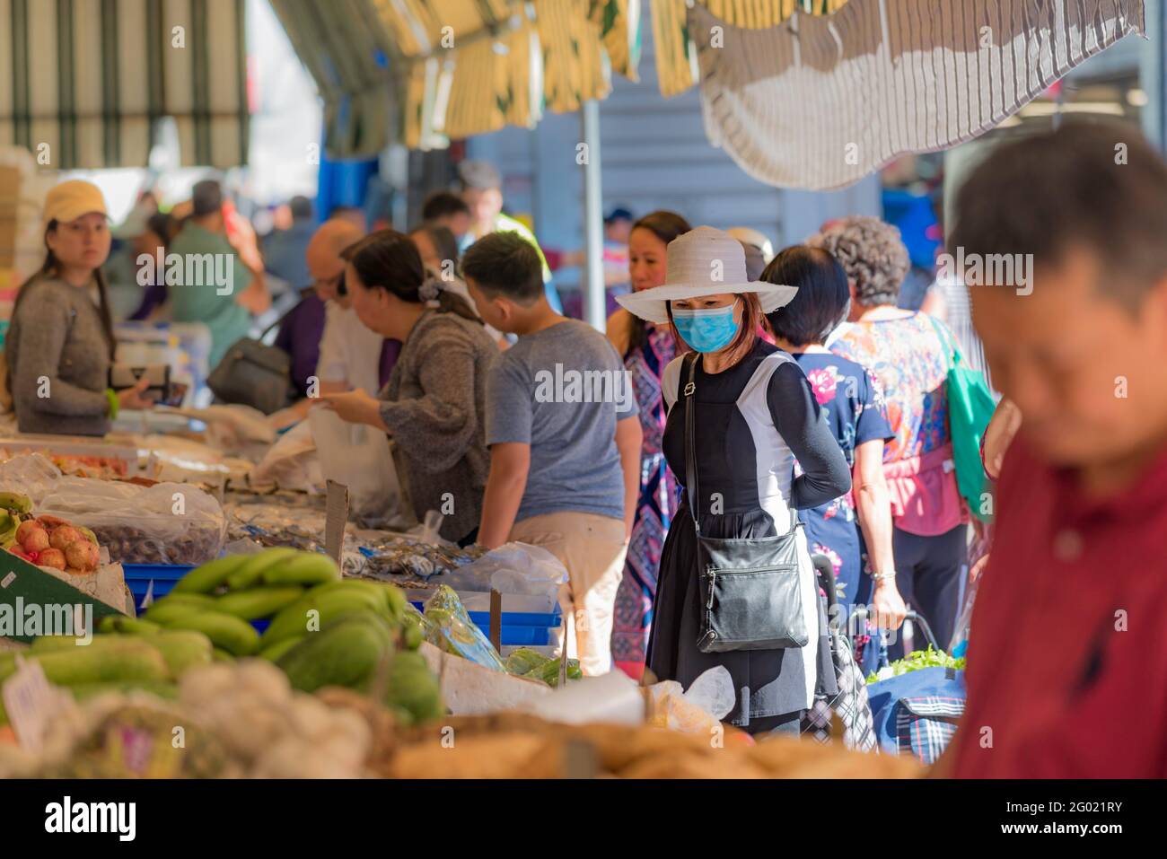 Mars 2021: Une femme portant un masque dans un marché de fruits et légumes en plein air bondé dans la banlieue de Sydney de Cabramatta, Nouvelle-Galles du Sud, Australie Banque D'Images