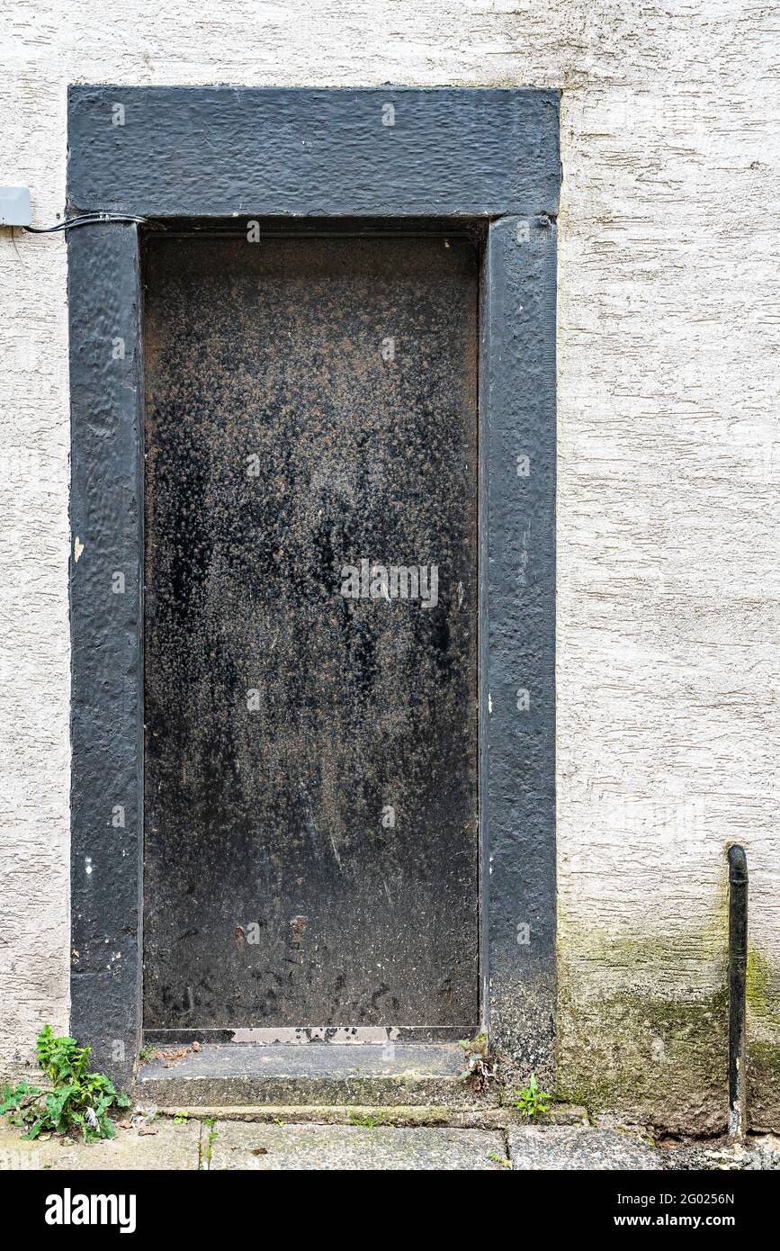 Encadrement de porte et de porte peint en noir sur un mur blanc contrasté Banque D'Images