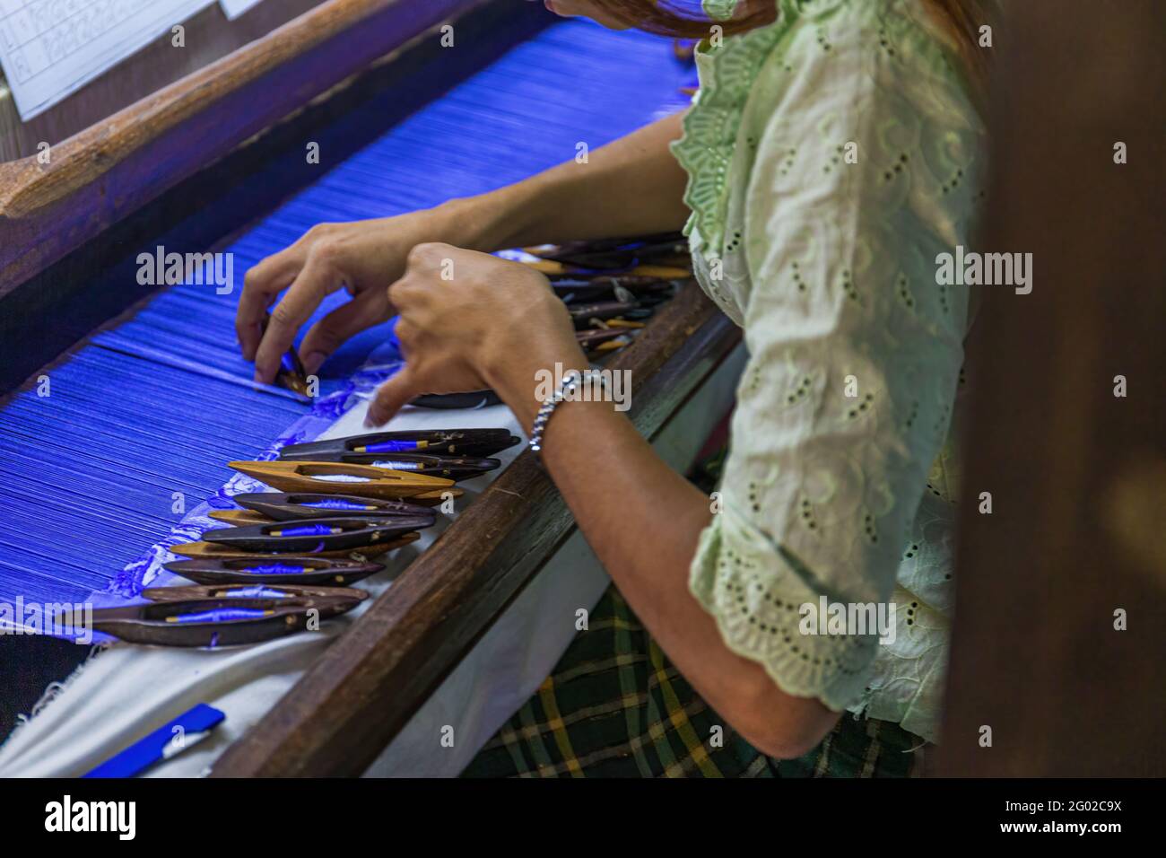 MANDALAY, MYANMAR - DÉCEMBRE 30 2017 : une femme birmane non identifiée qui vante de la soie dans l'une des nombreuses petites usines de Mandalay. Banque D'Images