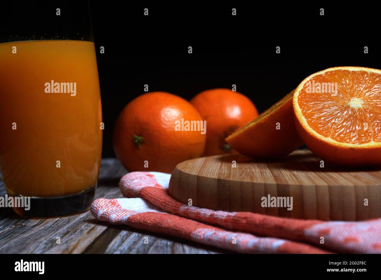 Pot en verre de jus d'orange frais fraîchement pressé avec des fruits frais sur une table en bois. Espace de copie et fond noir Banque D'Images