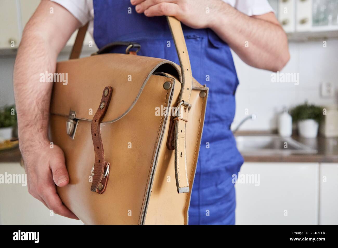 Artisan avec sac à outils sous son bras dans la cuisine en tant que service de réparation d'urgence Banque D'Images