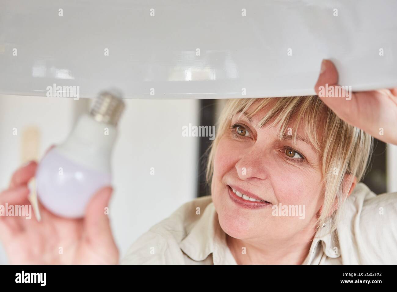 Femme transforme l'ampoule LED en ampoule pour économiser de l'énergie à accueil Banque D'Images