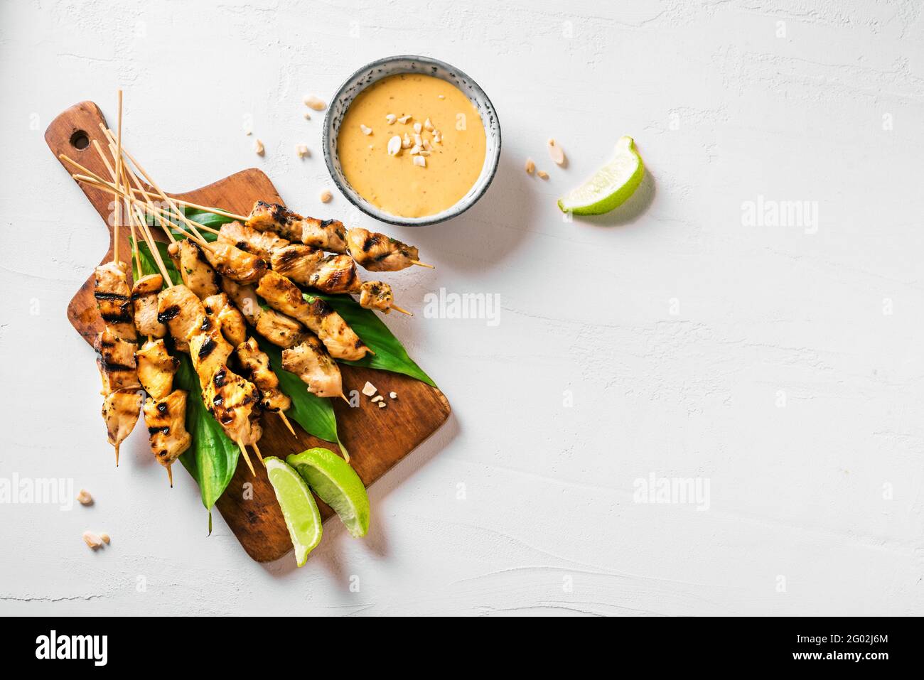 Brochettes de poulet grillé au satay servies avec de la sauce à la chaux et aux arachides sur fond blanc, espace de photocopie. Cuisine asiatique de style thaïlandais. Banque D'Images
