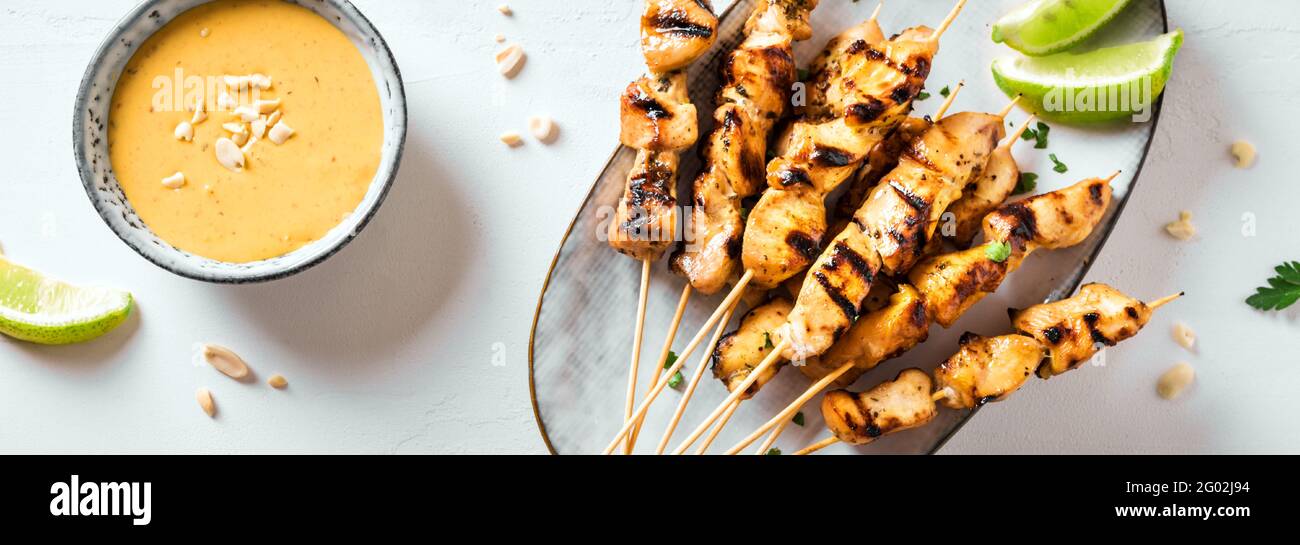 Brochettes de poulet grillé au satay servies avec de la sauce à la chaux et aux arachides, bannière. Cuisine asiatique de style thaïlandais. Banque D'Images