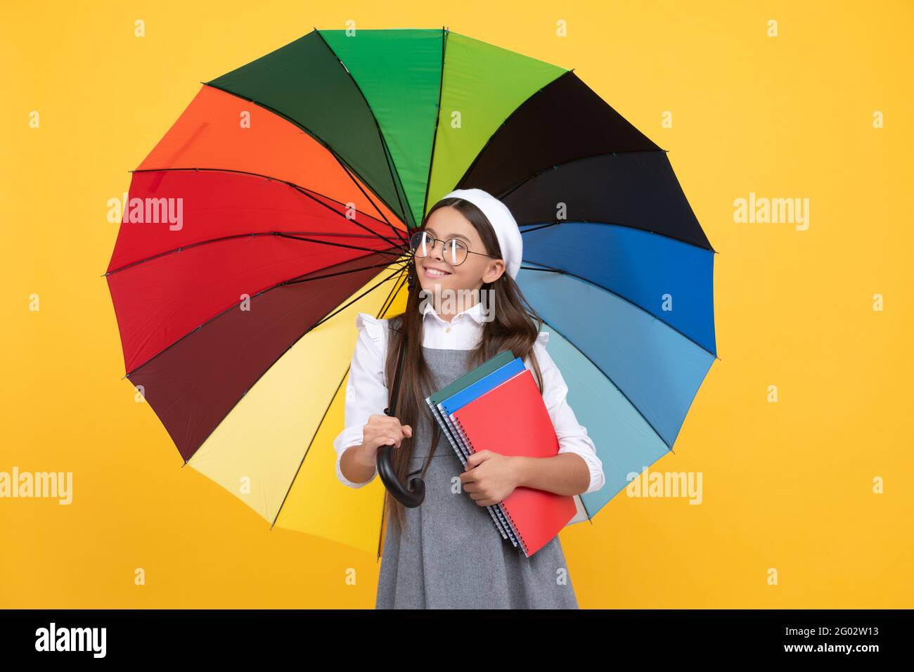 enfant en béret avec parapluie arc-en-ciel. saison d'automne. météo pluvieuse. retour à l'école. Banque D'Images