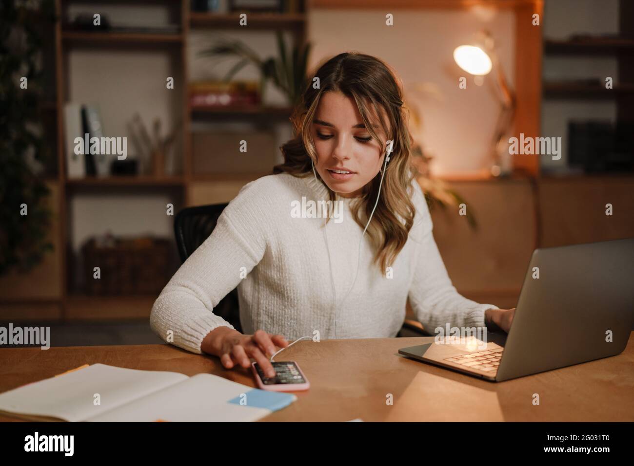 Femme d'affaires sérieuse dans les écouteurs regarder le webinaire sur ordinateur portable prendre des notes, apprendre à étudier l'ordinateur, faire un appel, participer en ligne confe Banque D'Images
