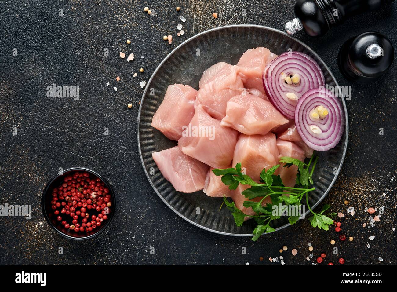 Morceaux crus ingrédients de viande de poulet sur bois, épices, herbes et légumes sur fond gris foncé. Ingrédients crus pour le goulash ou le shish keb Banque D'Images