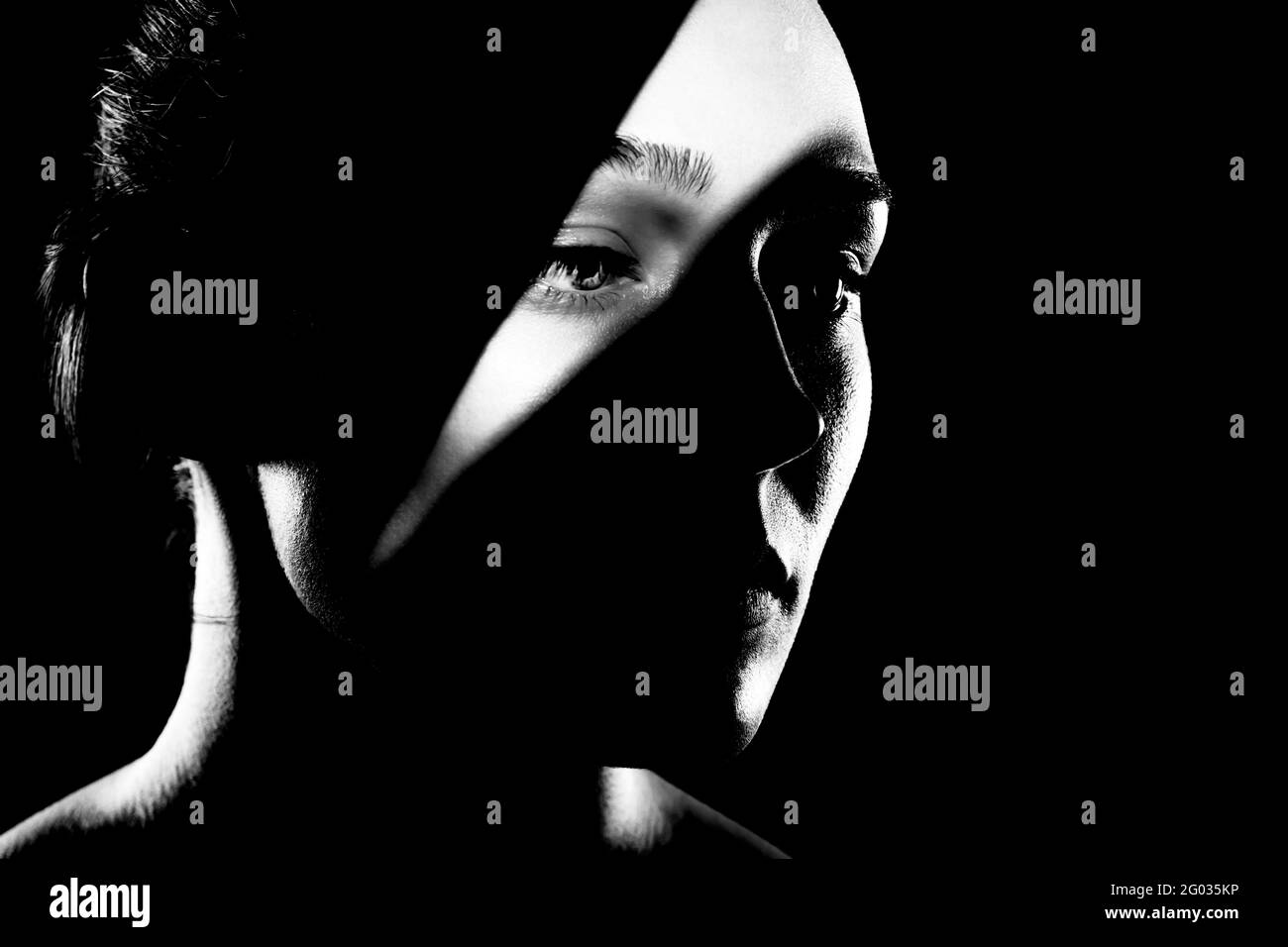 portrait studio d'une belle jeune femme avec des ombres sur son visage, contre le dos sombre. Photo en noir et blanc Banque D'Images