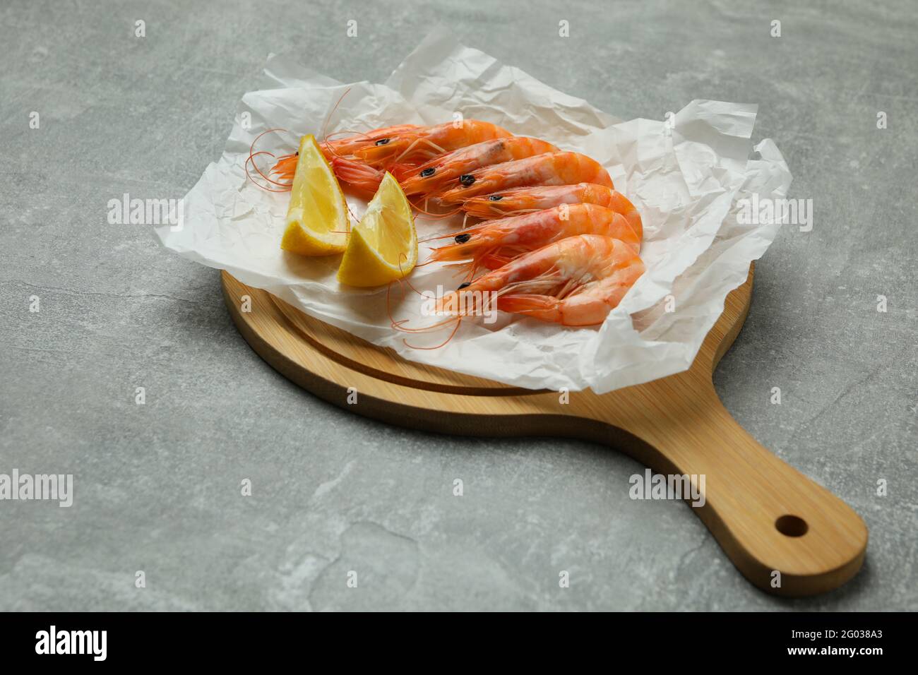 Embarquez avec des crevettes et du citron sur fond texturé gris Banque D'Images