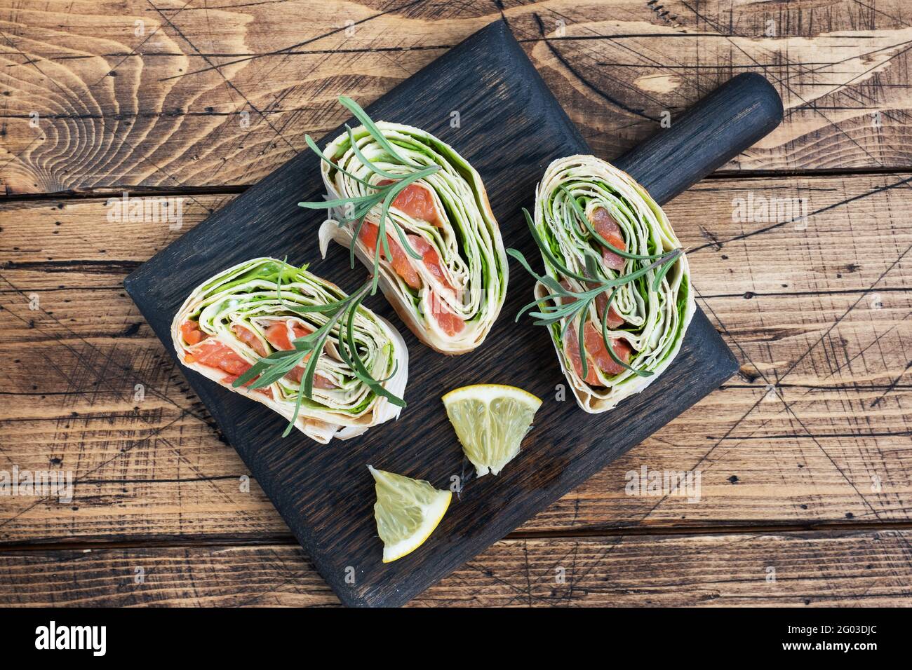 Rouleaux de pain pita fin et saumon rouge salé avec feuilles de laitue sur une planche à découper en bois. Copier l'espace Banque D'Images Rouleaux de pain pita fin et saumon rouge salé avec feuilles de laitue sur une planche à découper en bois. Copier l'espace Banque D'Images