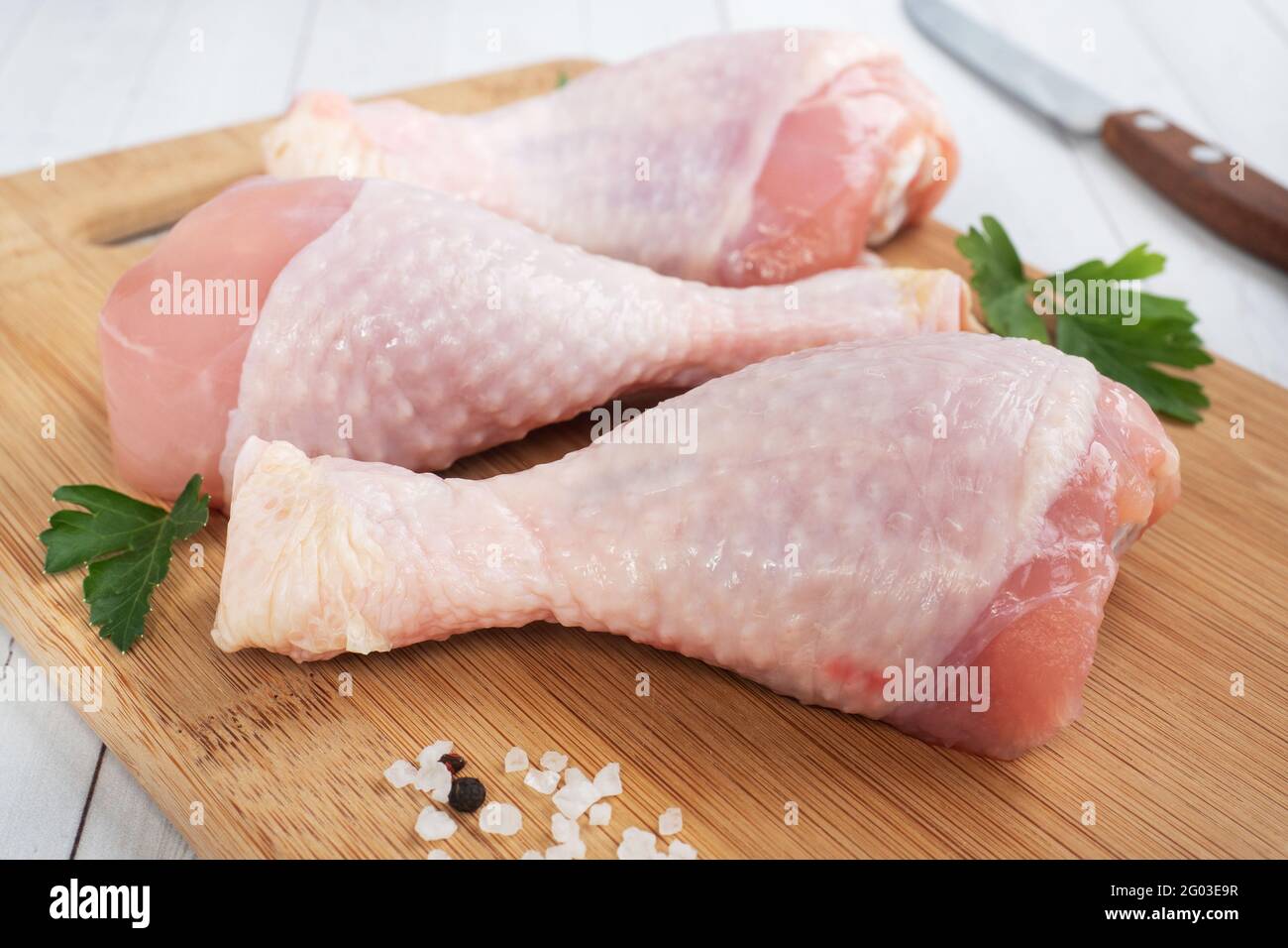 Pilons de poulet crus avec persil et épices sur un bois Planche à découper Banque D'Images Pilons de poulet crus avec persil et épices sur un bois Planche à découper Banque D'Images