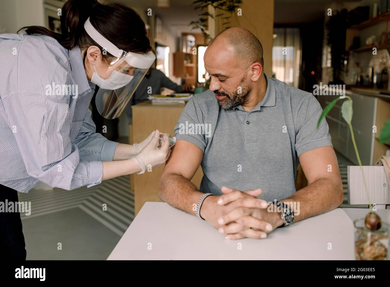 Une infirmière féminine s'injecte le vaccin COVID-19 chez un homme mature à la maison Banque D'Images