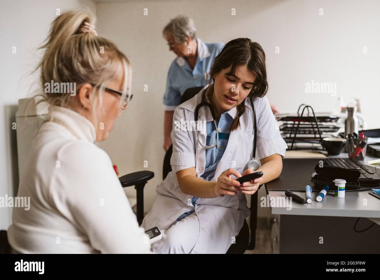 Une travailleuse de la santé discute de glaucometer avec le patient en clinique médicale Banque D'Images