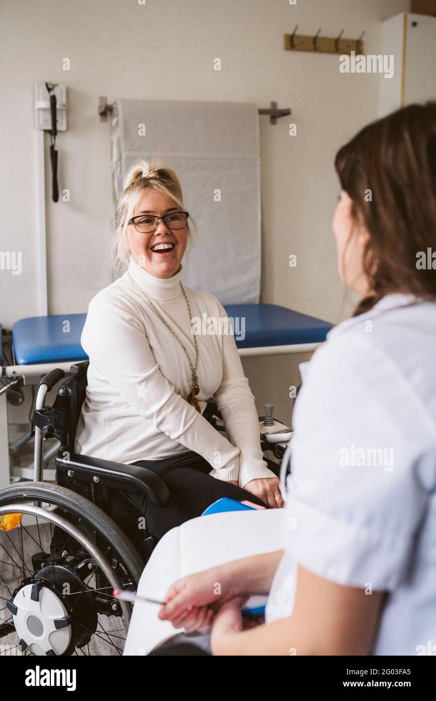 Gaie femme handicapée regardant la femme médecin dans la clinique médicale Banque D'Images