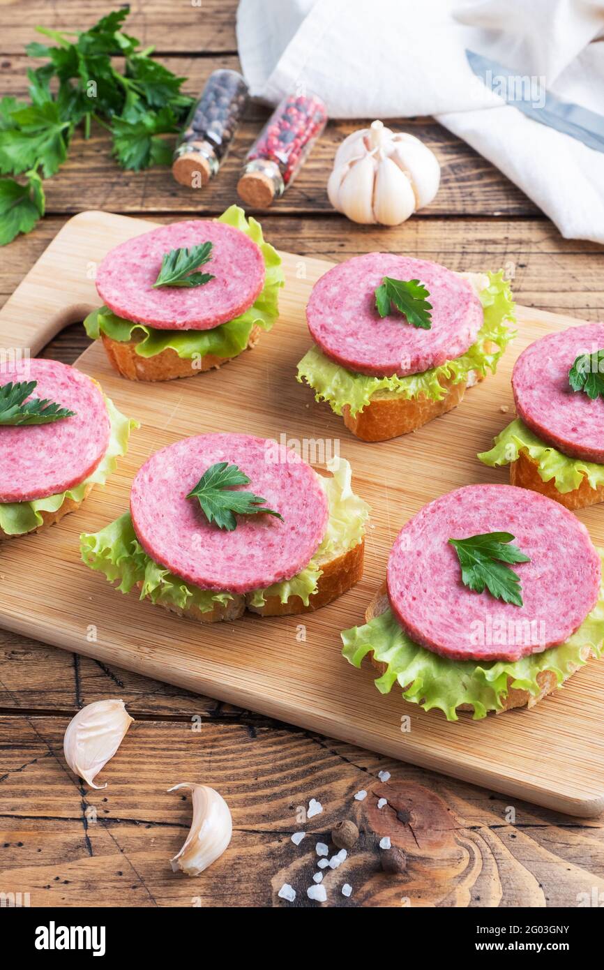 Sandwichs avec feuilles de laitue et saucisse de salami en tranches sur un Planche en bois Banque D'Images