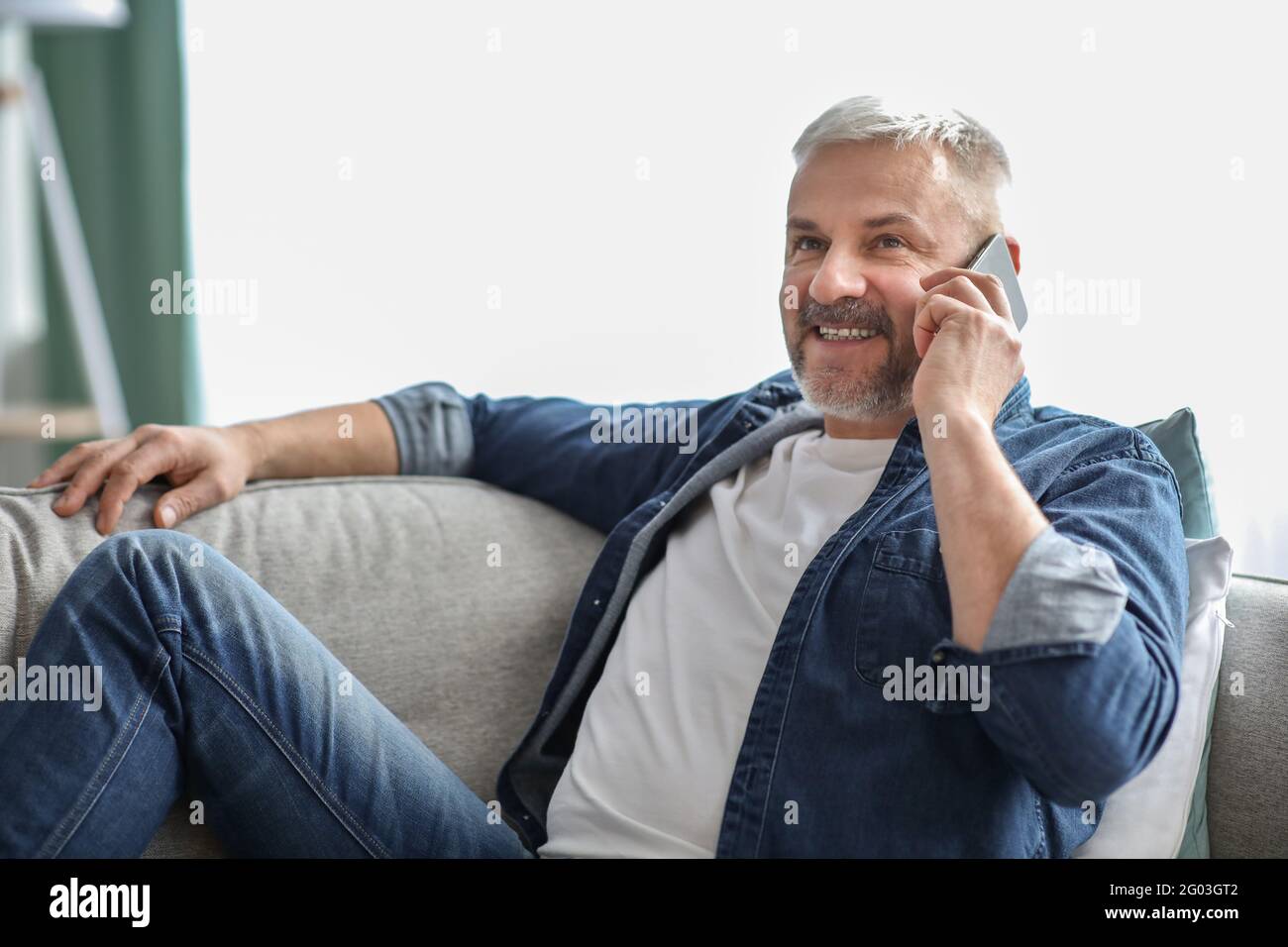 Vue latérale d'un homme senior souriant ayant une conversation téléphonique Banque D'Images