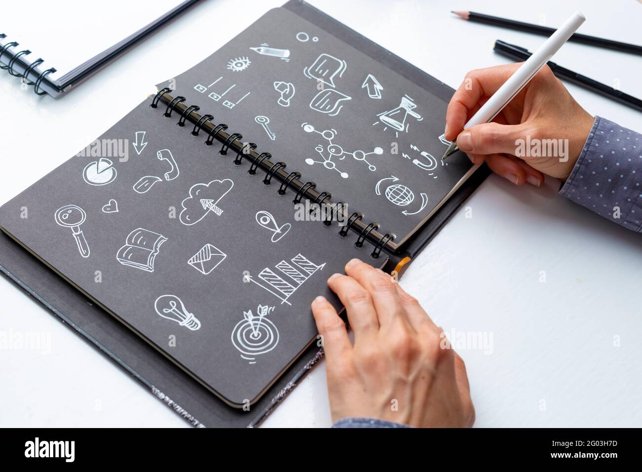Concept de symboles de marketing numérique. Les mains de designer de femme d'affaires dessinent des notes dans le carnet. Banque D'Images